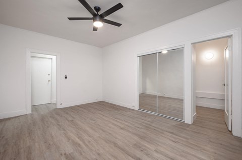 A room with a ceiling fan and light, wooden floors, and a glass door at Westmore Manor Apartments, California