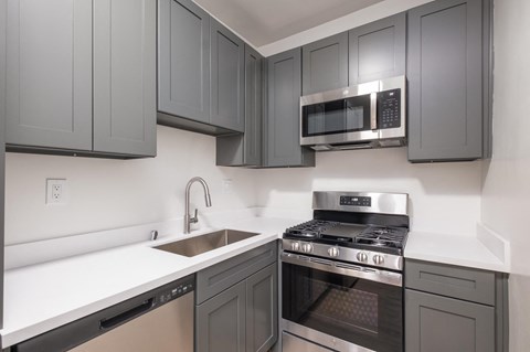 A kitchen with a stove, sink, and microwave.