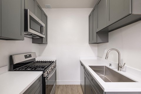 A modern kitchen with a stove, microwave, and sink at Westmore Manor Apartments, Los Angeles