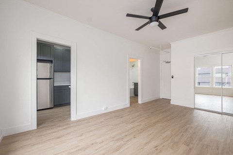 A spacious room with a ceiling fan and wooden flooring.