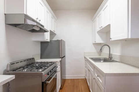 A kitchen with a stove, sink, and cabinets at Westmore Manor Apartments, Los Angeles, CA