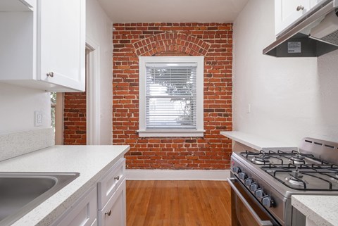 A kitchen with a brick wall and a stove top oven.