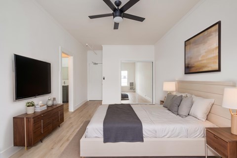 A bedroom with a bed, a ceiling fan, and a painting on the wall at Westmore Manor Apartments, Los Angeles, 90020