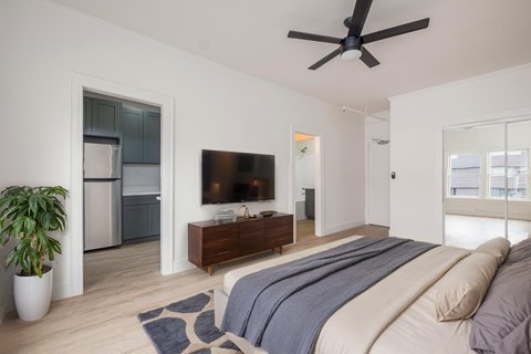 A bedroom with a bed, a television, and a plant at Westmore Manor Apartments, Los Angeles, CA
