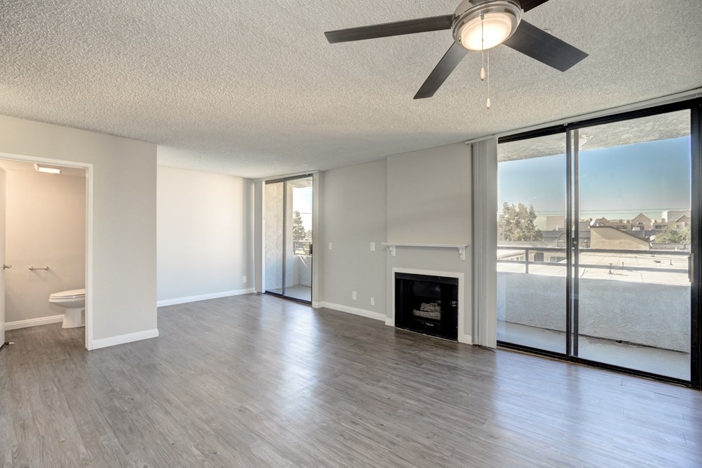an empty living room with a fireplace and a ceiling fan