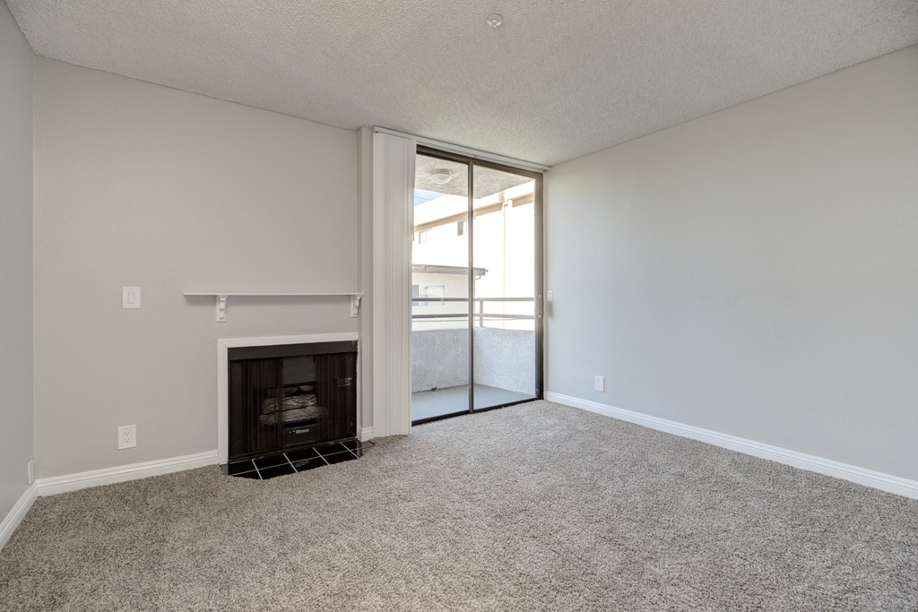an empty living room with a fireplace and sliding glass doors