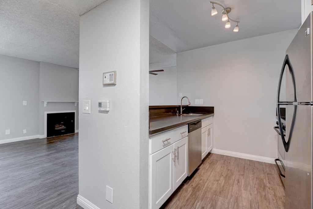 the kitchen and living room in a 2020s apartment with white appliances and wood floors