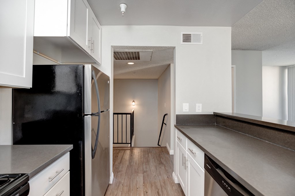 an empty kitchen with white cabinets and a black refrigerator