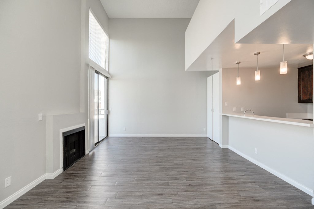 an empty living room with a fireplace and a kitchen