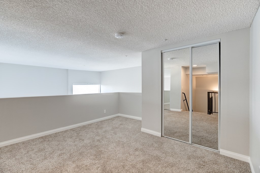 an empty living room with mirrored closet doors