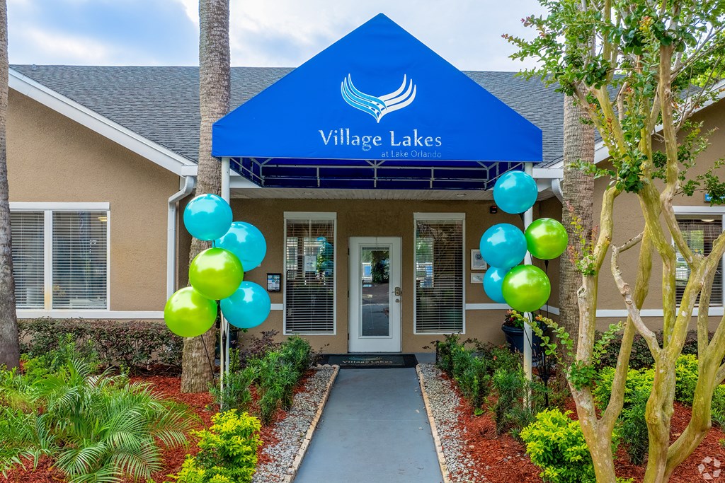 the front entrance to village lakes apartments with balloons and a blue roof