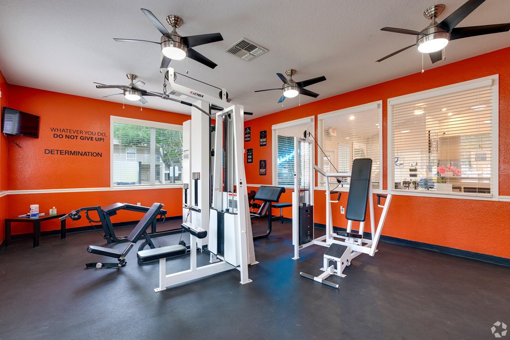 a gym with exercise equipment and ceiling fans