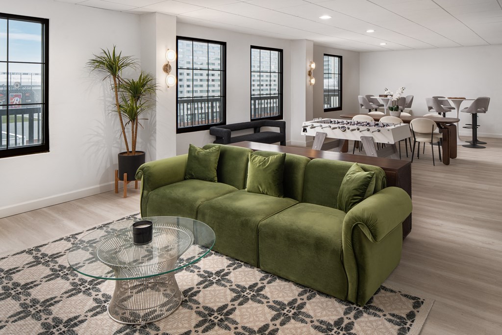 a living room with a green couch and a glass coffee table at Vision on Lombard, Baltimore