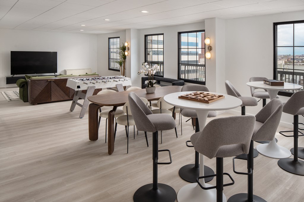 a living room with tables and chairs and a television at Vision on Lombard, Baltimore, MD 21201