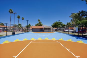 A basketball court with a blue and orange surface and white lines.