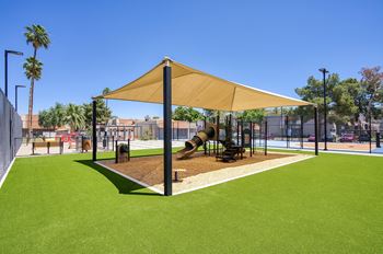 A playground with a yellow canopy and a slide.