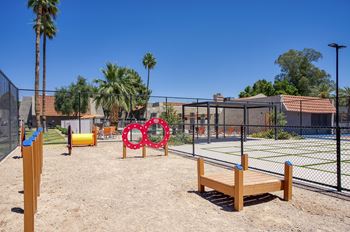 A playground with a wooden bench, a fence, and a swing set.