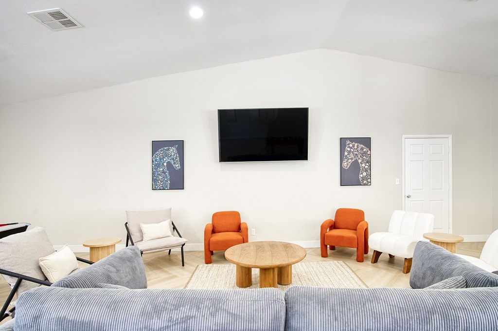 A living room with a blue couch and a television on the wall.