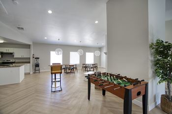 A foosball table is in the middle of a kitchen and dining area.
