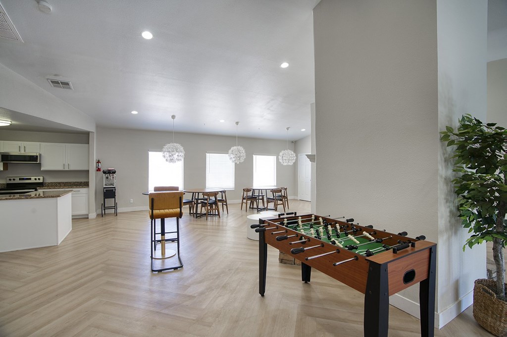 A foosball table is in the middle of a kitchen and dining area.