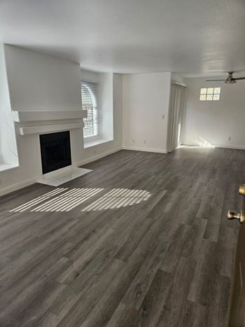 an empty living room with wood floors and a fireplace