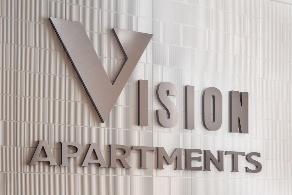 a rendering of the logo for v stop apartments on a white wall at Vision on Lombard, Baltimore, MD