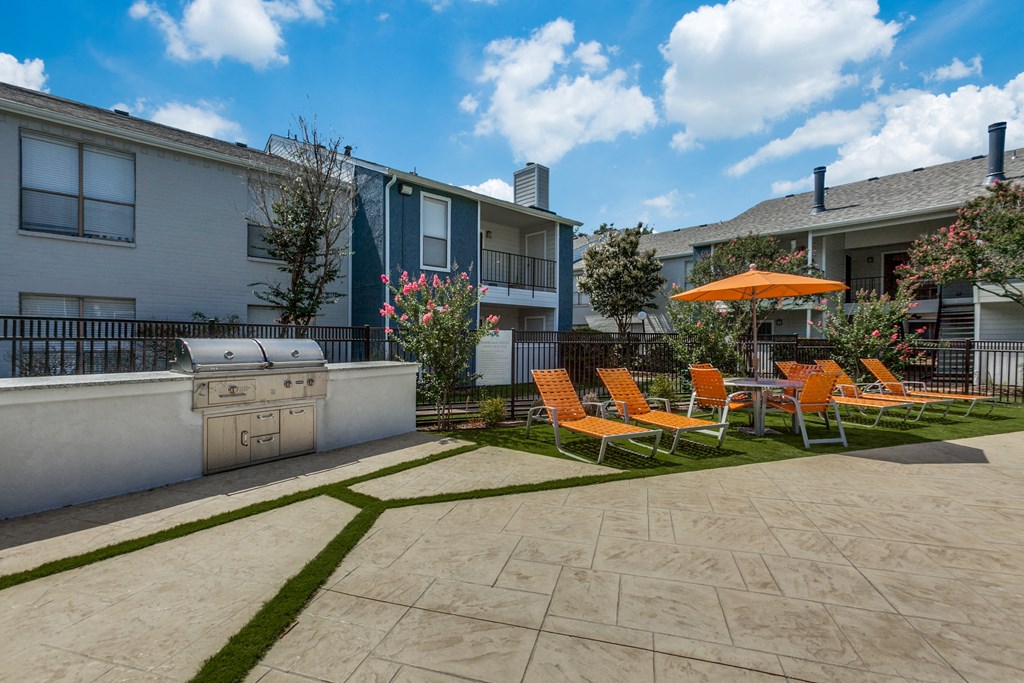 a patio with chairs and an umbrella and a grill at Seacrest Apartments, Texas