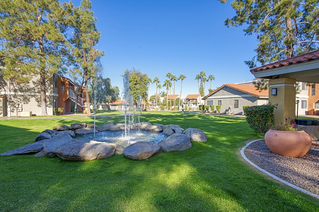 A garden with a fountain and a large pot.