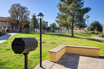 A black mailbox and a lamp post stand on a grassy area next to a brick structure.
