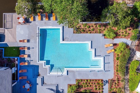 A swimming pool surrounded by a concrete patio and a green lawn.