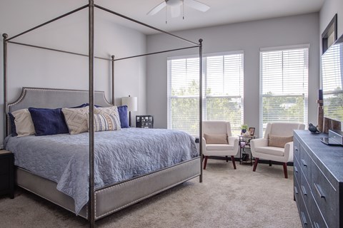 A bedroom with a four poster bed and a chair.