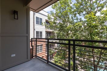 A balcony with a metal railing and a tree in the background.