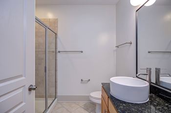 A bathroom with a white sink, toilet, and a glass shower stall.