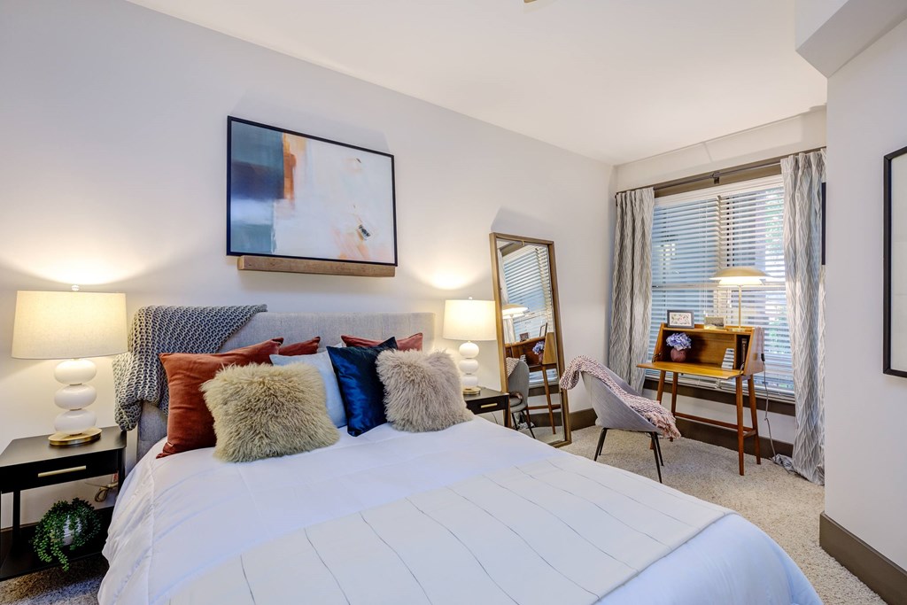 A bedroom with a large bed and a painting on the wall.