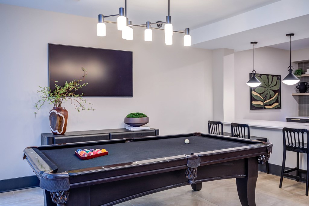 A pool table in a room with a TV on the wall.