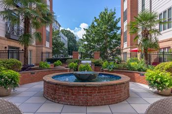 A small fountain in the middle of a courtyard surrounded by potted plants.