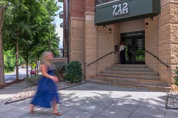 A woman in a blue dress walks past a building with a sign that reads 712 Tucker.