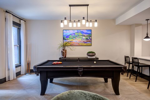 A  room with a pool table and a TV on the wall.