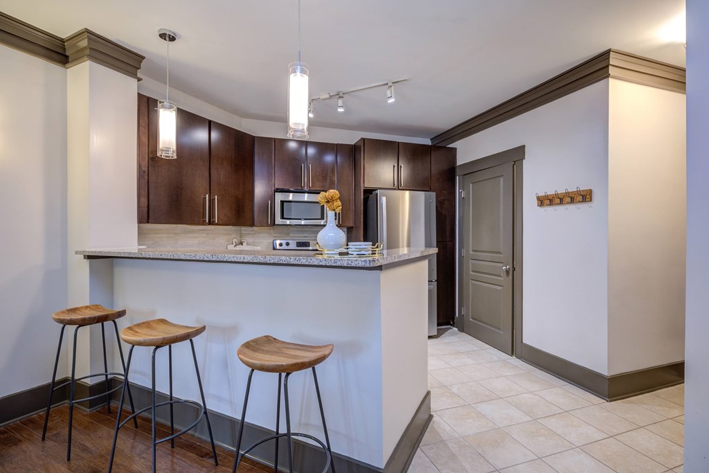 A kitchen with a white counter and brown bar stools.