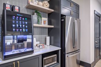 A modern kitchen with a fridge and a coffee machine on the counter.