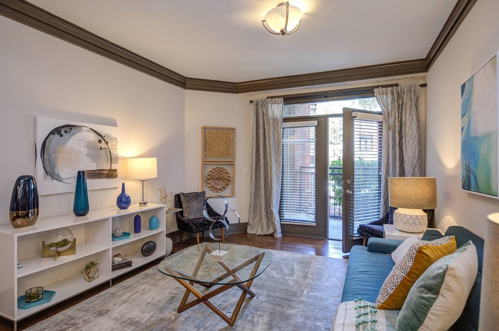 A living room with a blue couch and a glass coffee table.