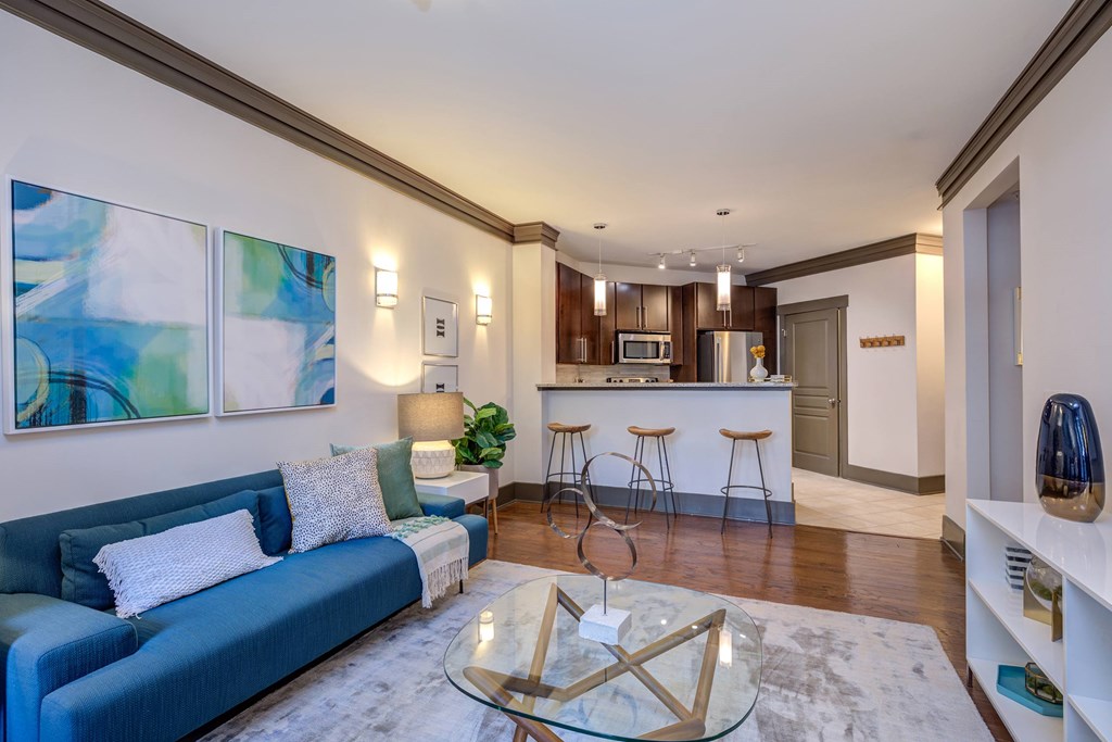 A modern living room with a blue couch and a glass coffee table.