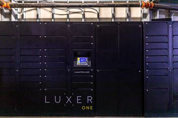 A row of black lockers with the word LUXER ONE written on them.