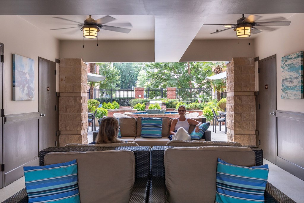Two people sitting on a couch in a room with a ceiling fan.