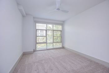 A room with a carpeted floor and a window with blinds.