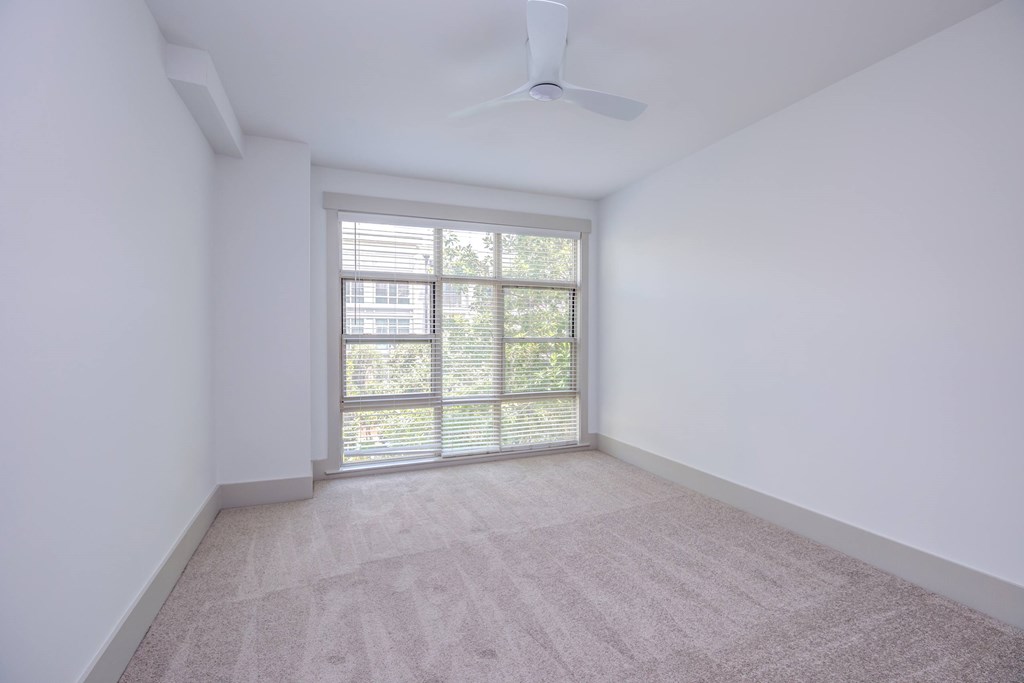 A room with a carpeted floor and a window with blinds.