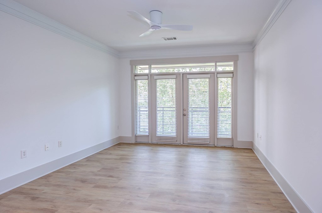 A room with a ceiling fan and glass doors.