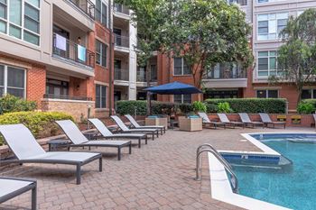 A pool surrounded by lounge chairs and umbrellas.