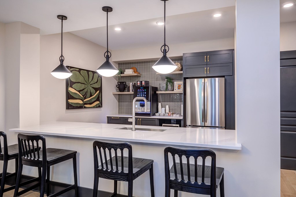 A kitchen with a white counter and black chairs.