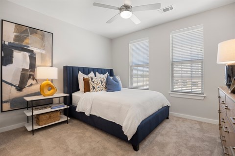 A bedroom with a bed, nightstand, and a ceiling fan.